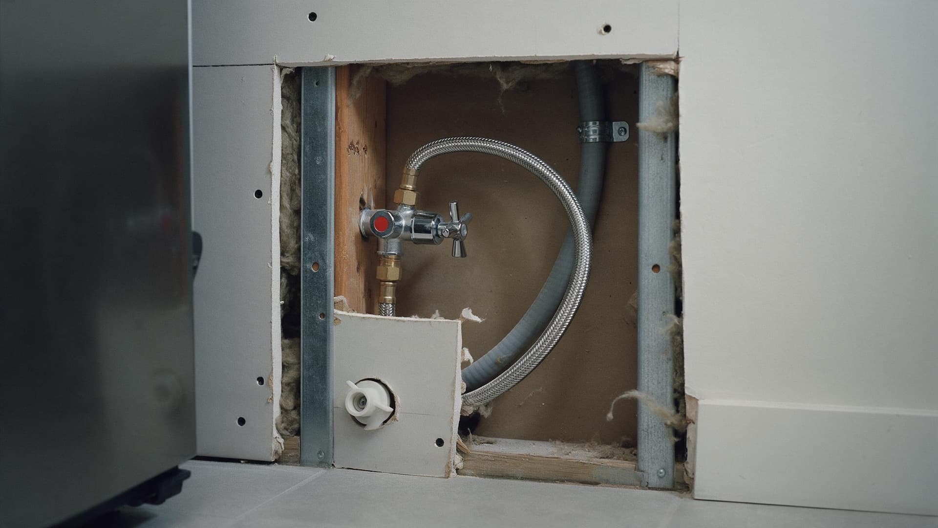 Cold water isolation valve and braided flexible hose in a wall cavity behind a fridge