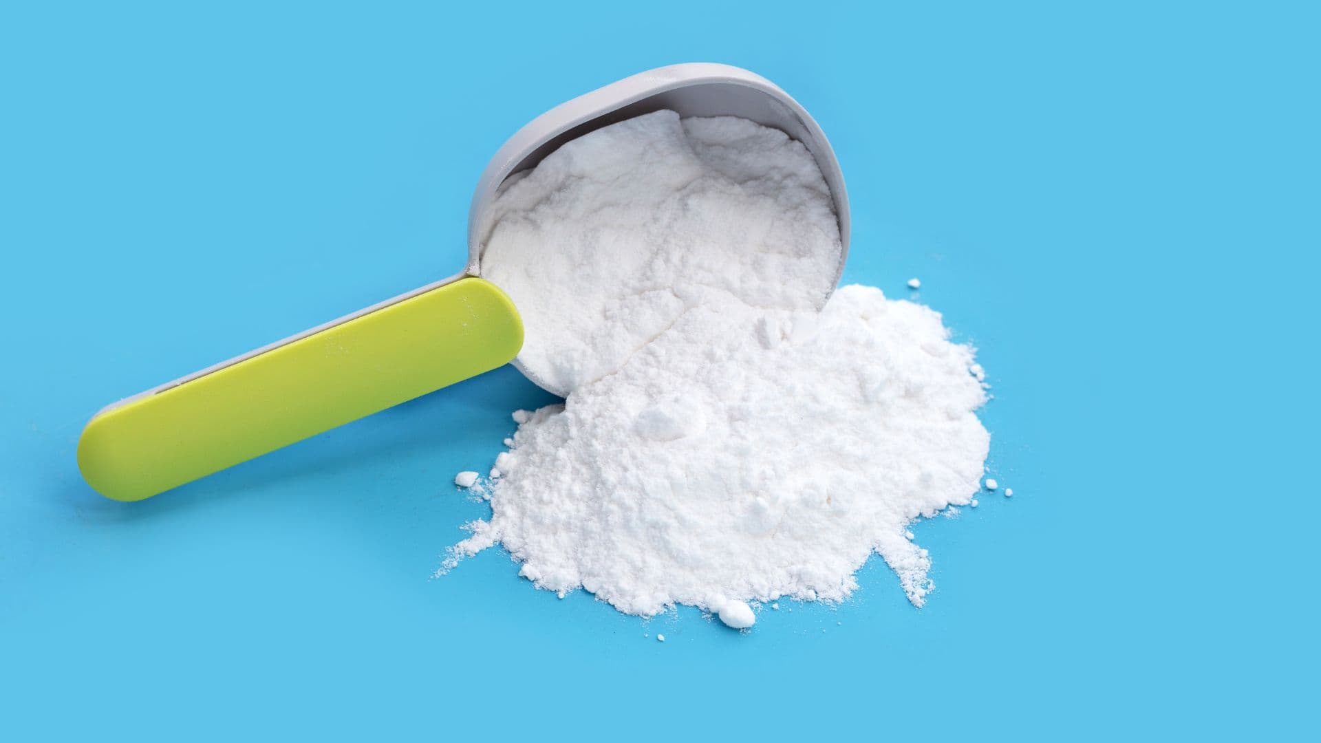 Scoop of baking soda tipped out onto a blue background