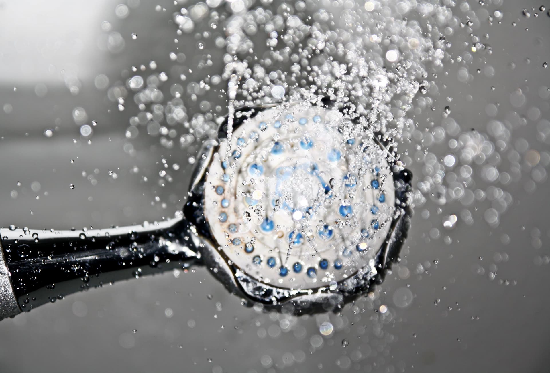 Chrome shower head running warm water in a modern bathroom