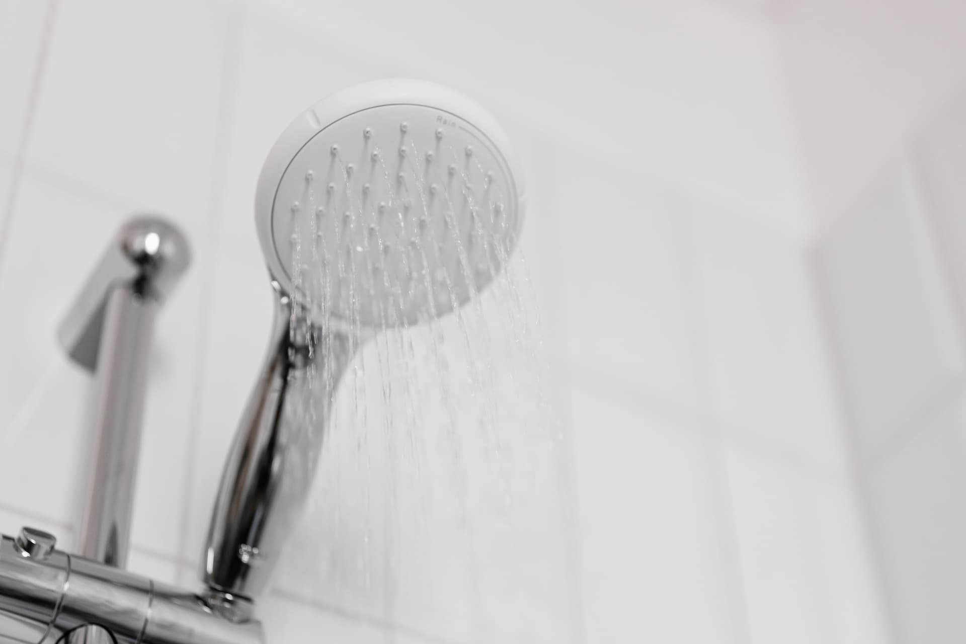 Close up of a chrome shower head dripping water