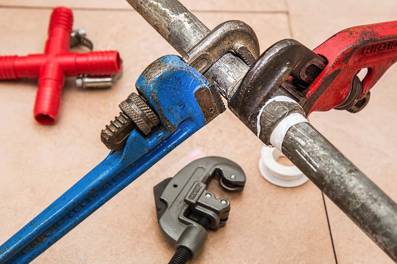 Adjustable wrench and plumbing tools laid out for a DIY pipe repair job