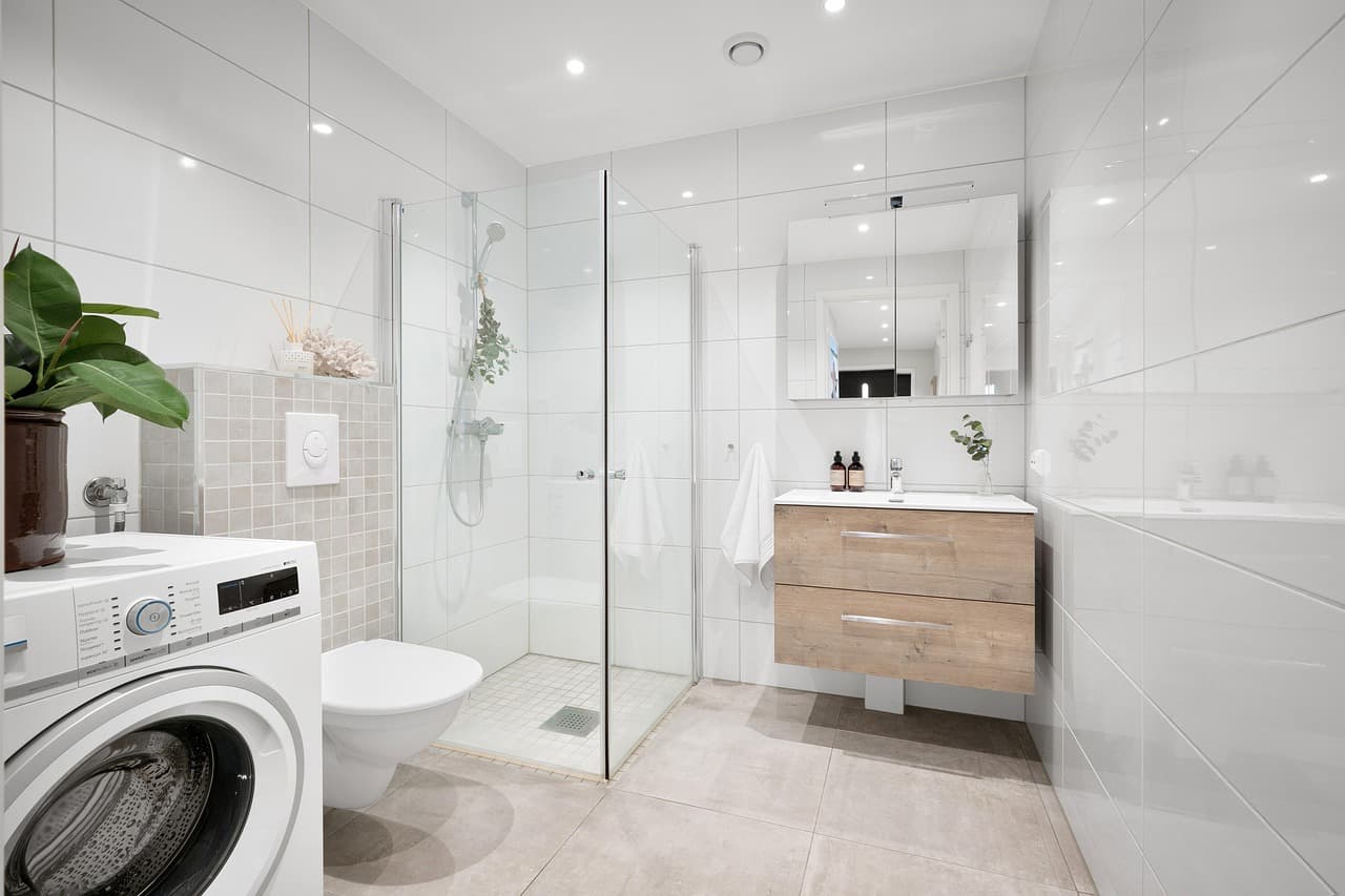 Clean white toilet in a modern bathroom with shower and tiled walls